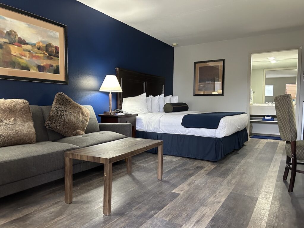 Hotel guest room with large queen bed, spacious seating area, work desk, and ensuite bathroom. Hotchkiss Inn, Hotchkiss, Colorado.