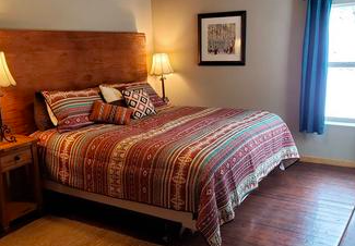 Cozy bed in mountain-themed cabin bedroom. Lodge at Needle Rock hotel cabins, Crawford, Colorado.