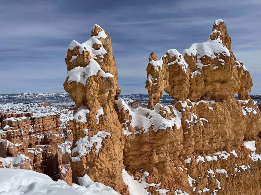 Intricate red rock hoodoo covered in patches of snow on sunny summer day. Hiking Queen's Garden via Navajo Loop in Bryce Canyon National Park, Utah.