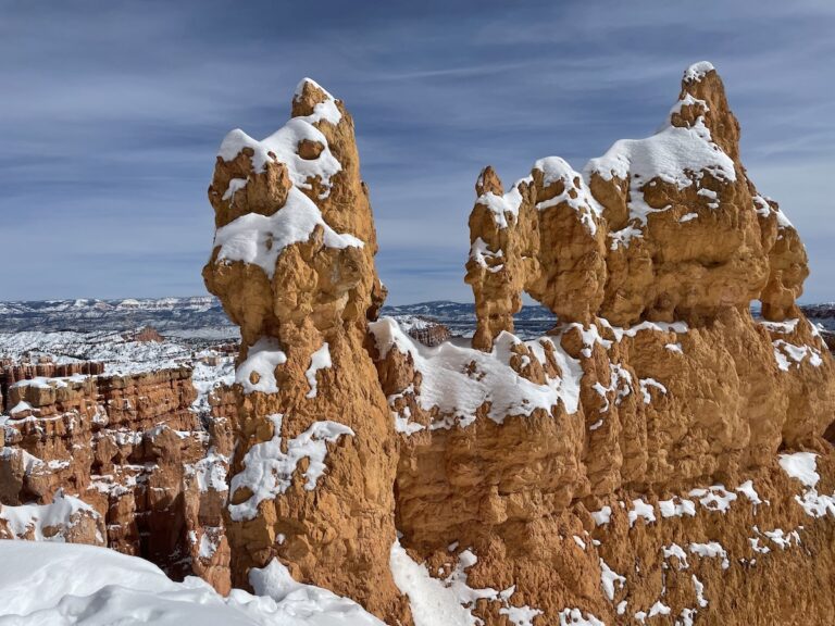 Intricate red rock hoodoo covered in patches of snow on sunny summer day. Hiking Queen's Garden via Navajo Loop in Bryce Canyon National Park, Utah.