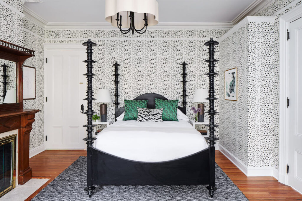 Guest hotel room with four-poster bed, fireplace, funky wallpaper, and wood floors. Cliffside Inn hotel, Newport, Rhode Island.