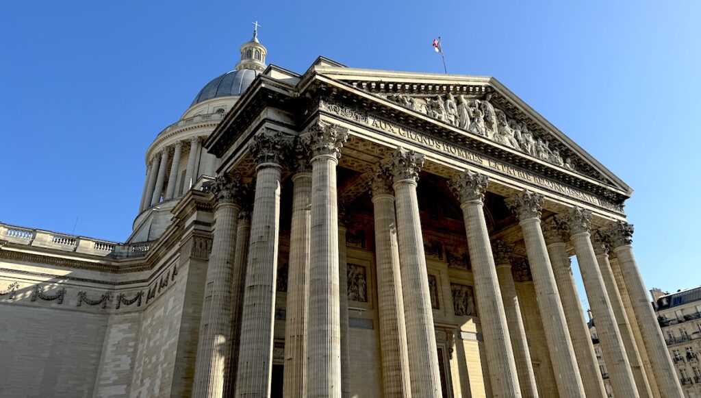 Neoclassical monument with large Greek-style pillars and domed building on sunny day. Paris Pantheon, Paris, France.