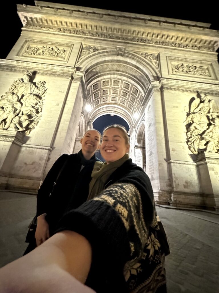 selfie of women in front of Arc de Triomphe at night Paris France