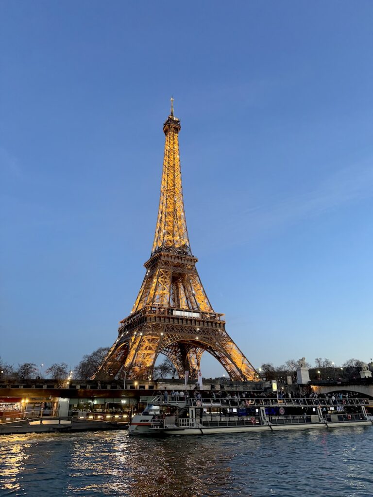 view of sparkling eiffel tower from boat tour on seine river Paris France