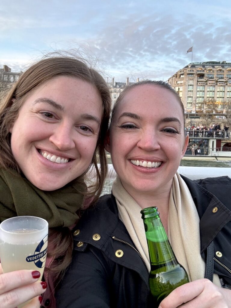 women smiling with drinks on boat sunset happy hour cruise seine river paris france