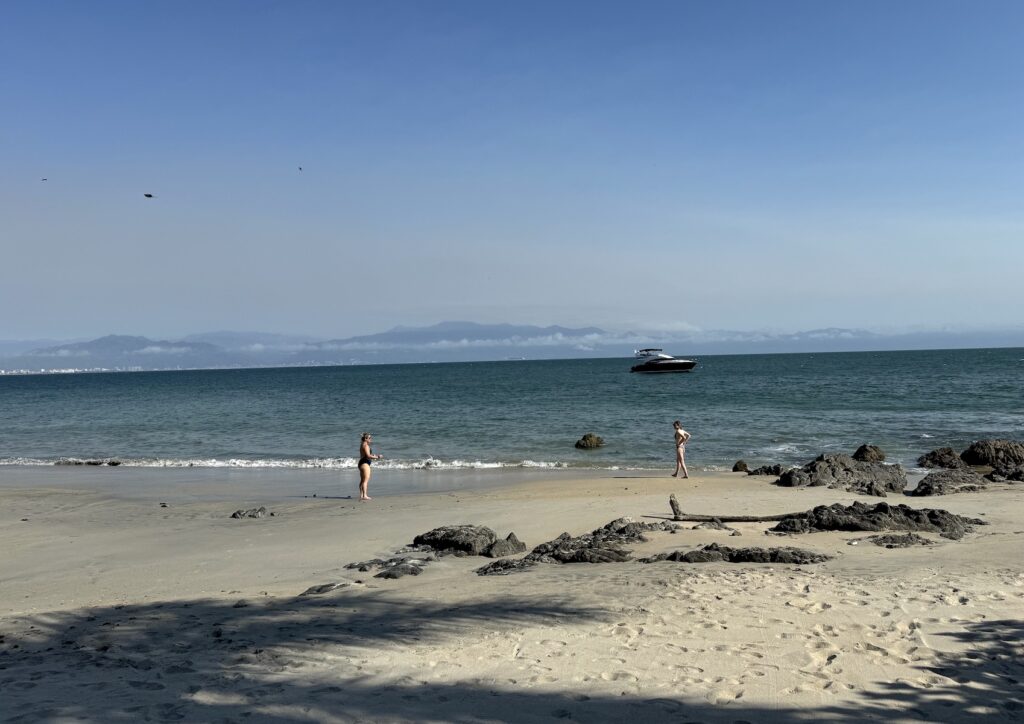 women walking on sandy beach with yacht in background near puerto vallarta and punta mita Mexico