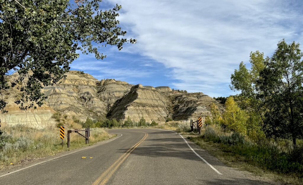 Scenic drive winding through colorful badlands on sunny day, Theodore Roosevelt National Park North Unit, North Dakota.
