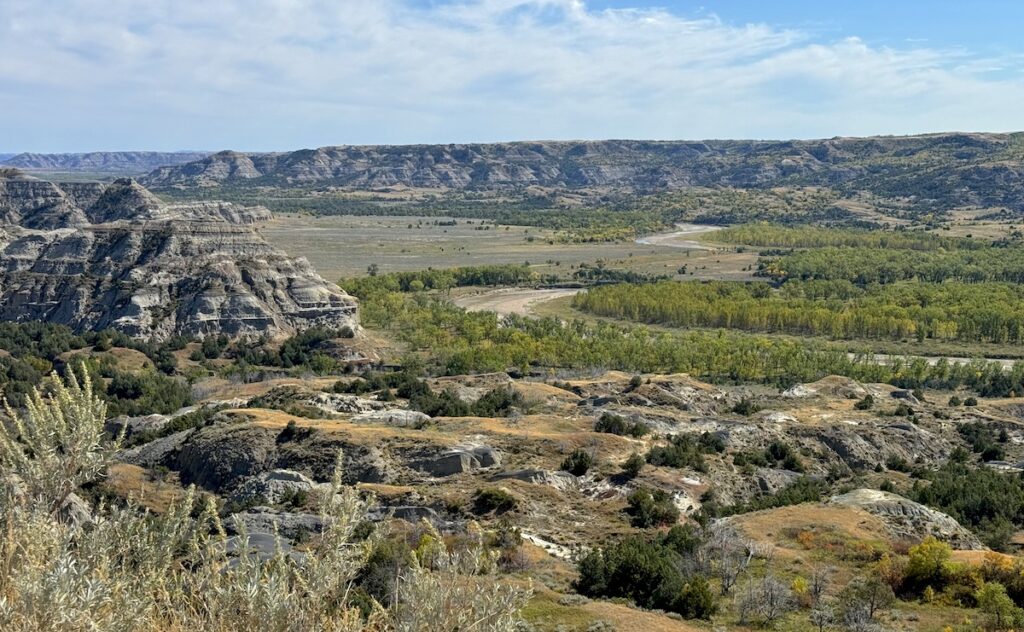Dramatic view of badlands and Little Missouri River with early fall colors on sunny day, Caprock Coulee Loop, Theodore Roosevelt National Park North Unit, North Dakota.