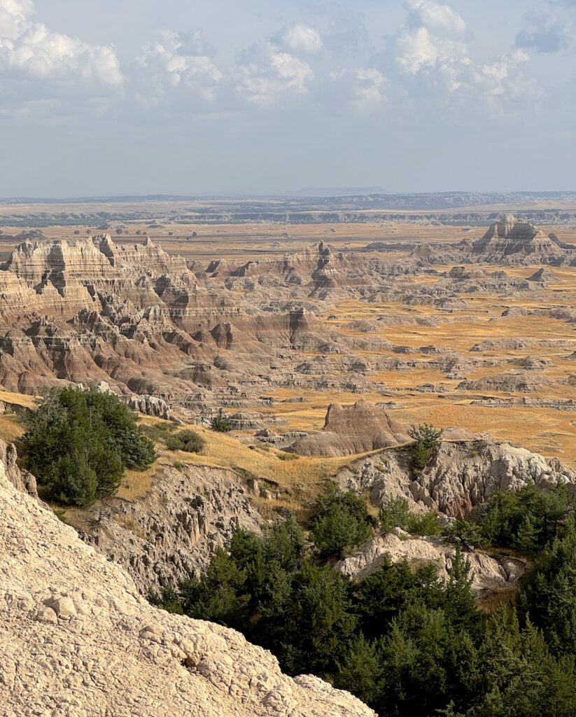 View from hiking trail of colorful badlands surrounded by prairies on sunny day. Notch Trail, Badlands National Park, South Dakota.