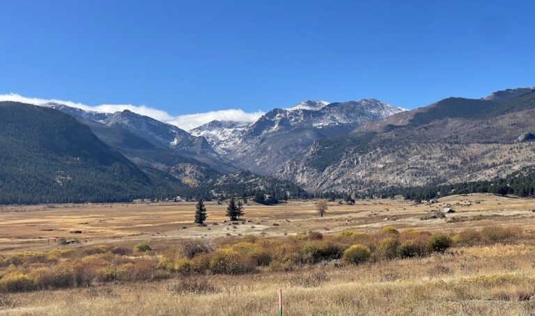 Open meadow with dramatic mountain peaks in background on sunny fall day. Moraine Park, Rocky Mountain National Park, Colorado.