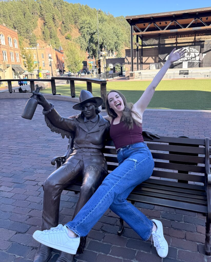 woman posing with statue main street deadwood south dakota black hills