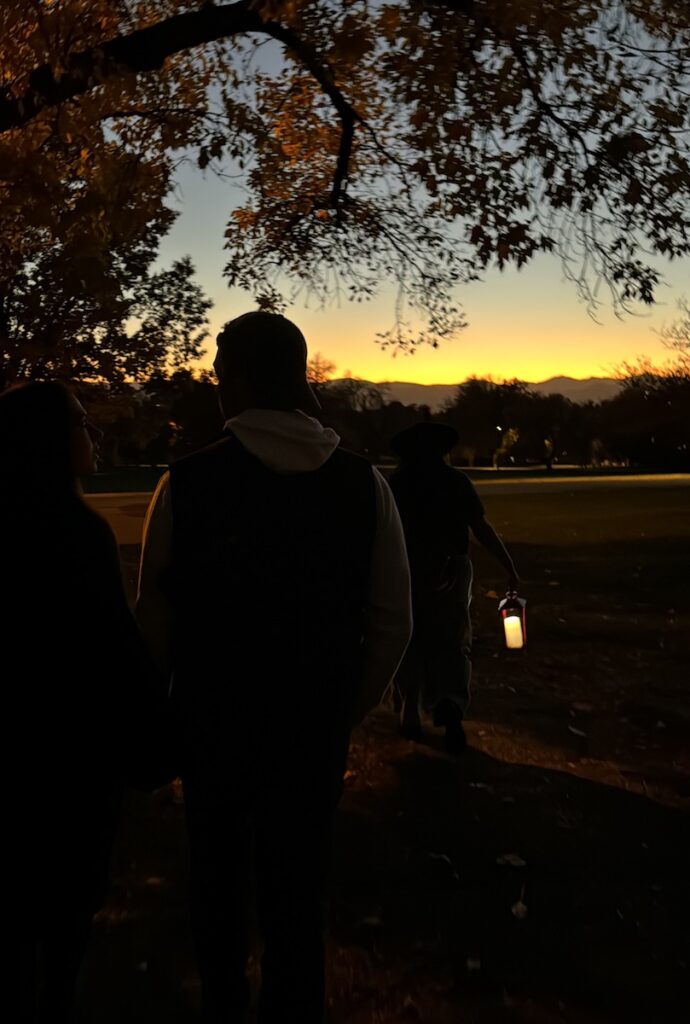 Group tour following tour leader with lantern at dusk. Cheeseman Park Ghost Tour, Denver Local Tours, Denver, Colorado halloween.