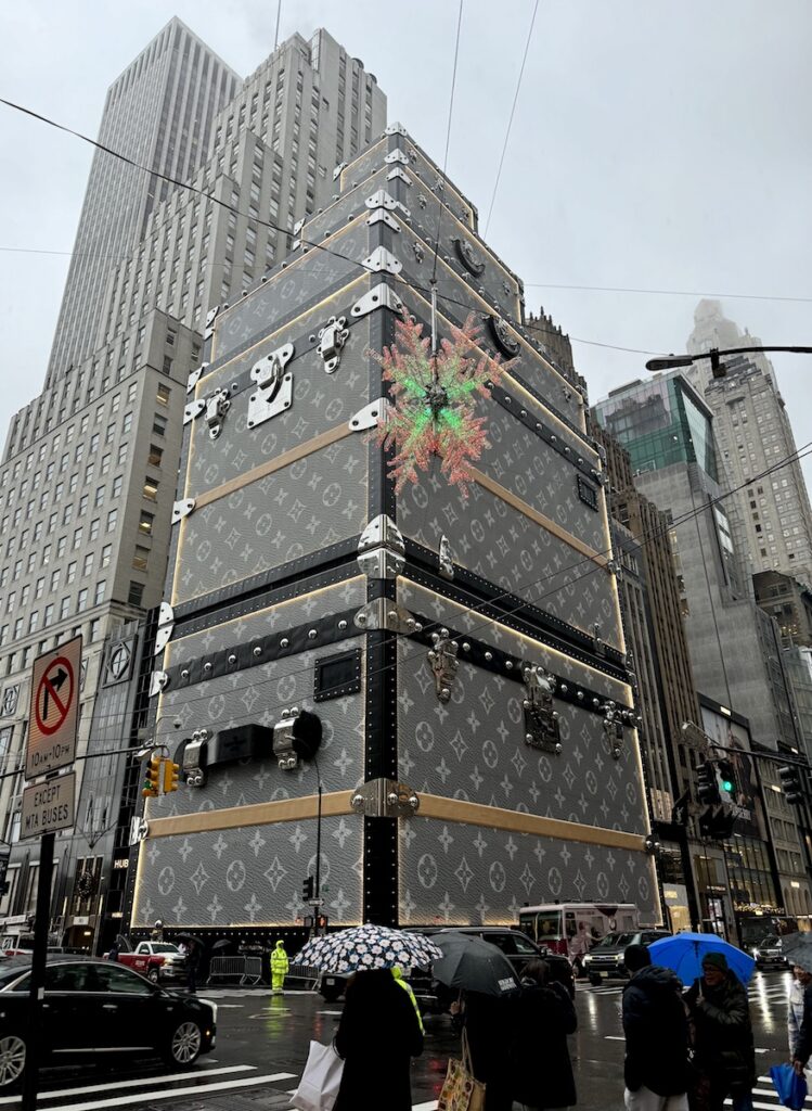 High rise buildings on gloomy afternoon with front building covered in scaffolding that looks like Louis Vuitton Luggage stacked together. Louis Vuitton Flagship Store, Fifth Avenue, Midtown Manhattan, New York City, New York.