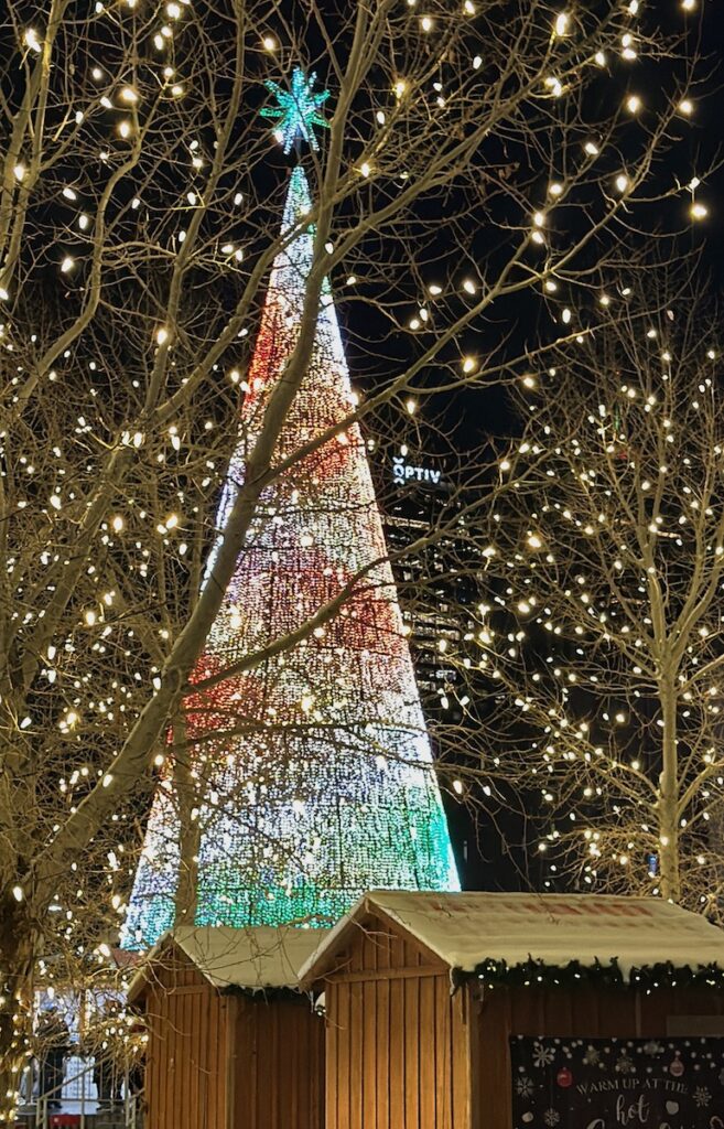 Giant electronic Christmas lit up in multi-color in center of Christmas market at night. Denver Chriskindlmarket, Denver, Colorado.