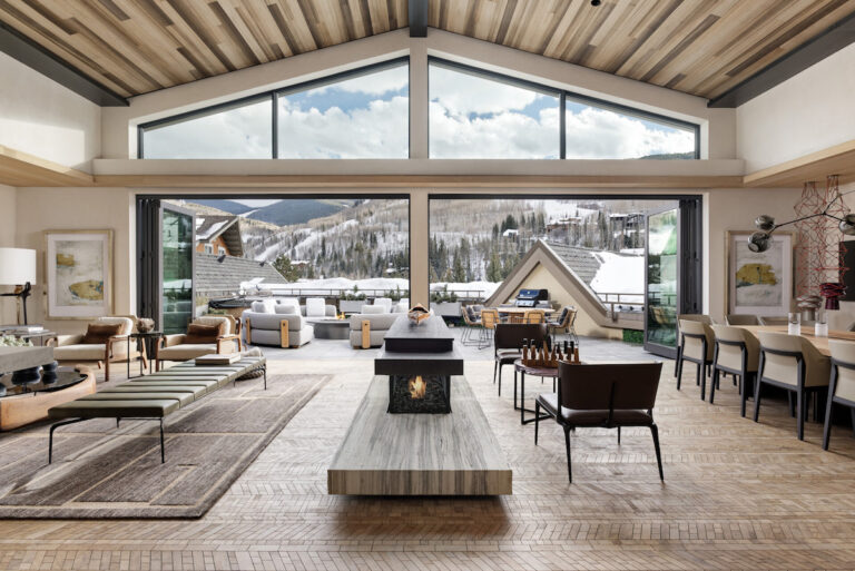 Luxury hotel guest area with large open seating areas open to outdoor balcony overlooking snow-covered mountains on sunny winter day. Four Seasons Resort & Residences Vail, Vail, Colorado.