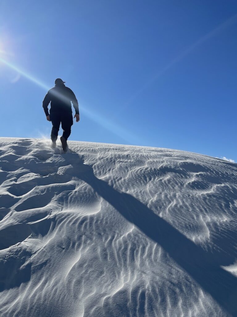 man climbing steep sand dunes backcountry camping loop trail white sands national park new mexico