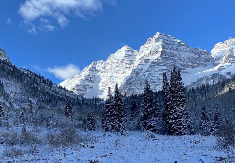 Pair of mountain peaks striped with snow on sunny winter day. Maroon Bells, Aspen, Colorado.