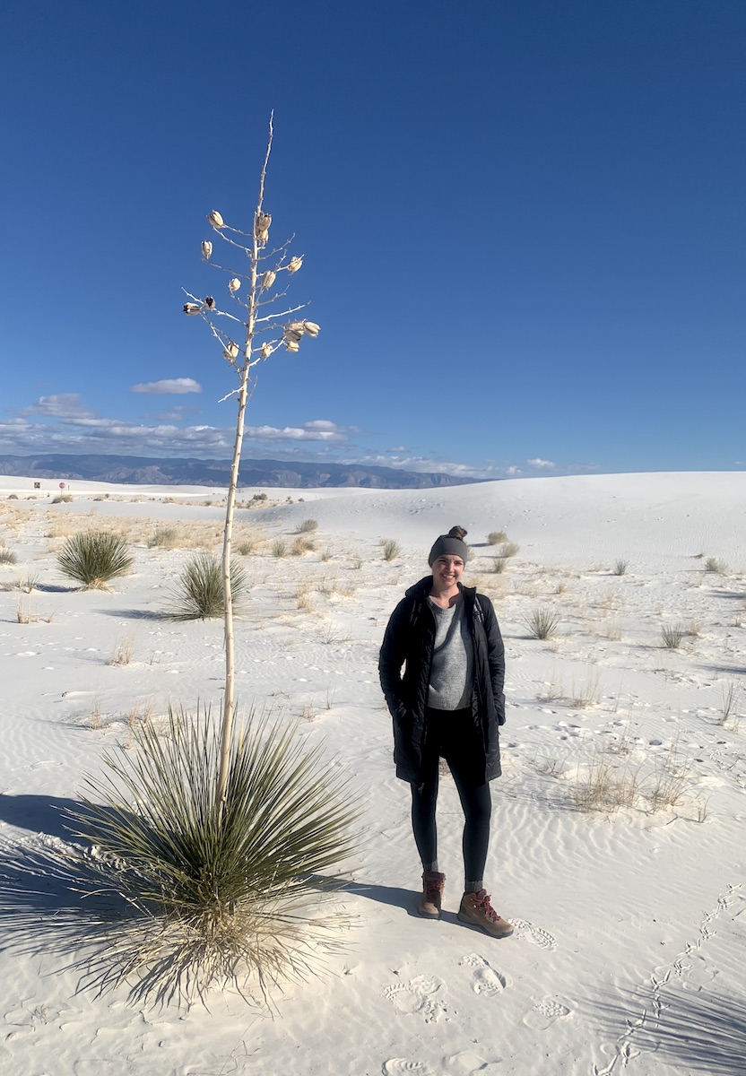 woman hiking next to yucca in sand dunes white sands national park new