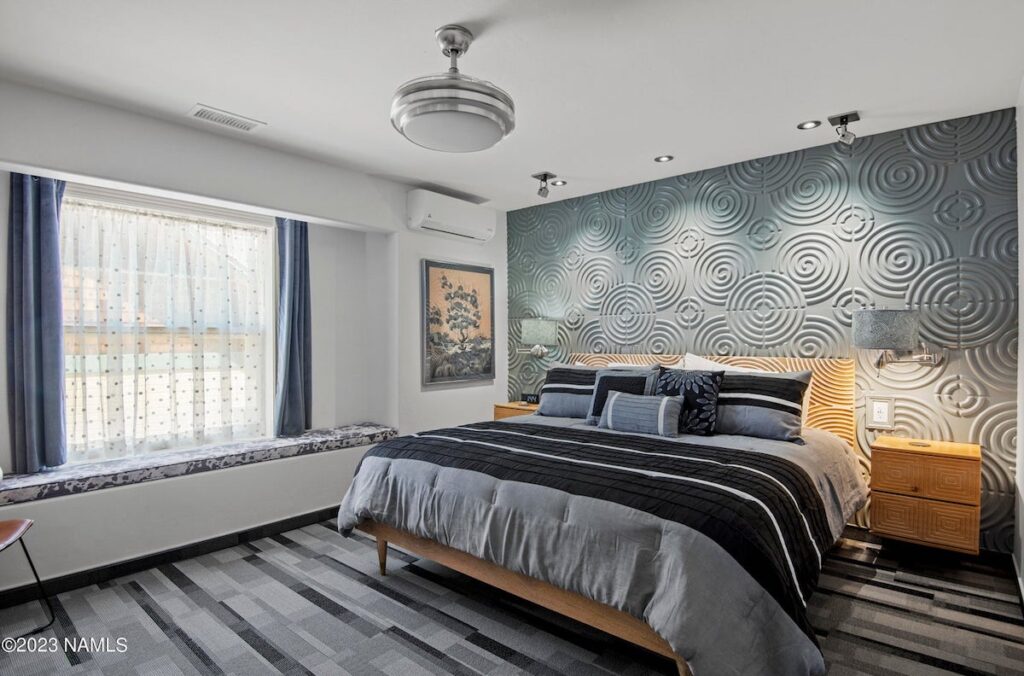 Guest room with grey textured walls, large king bed and window sill seating area. 303 BnB Inn, Flagstaff, Arizona.