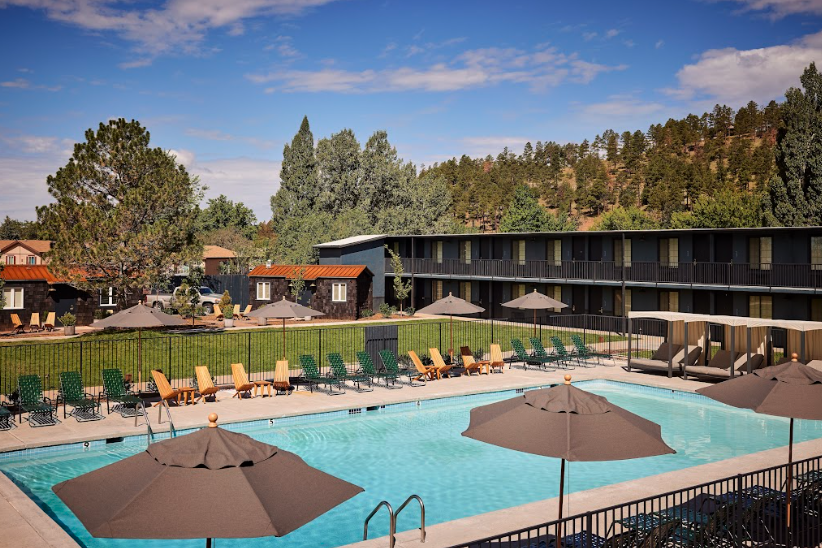 Hotel pool next to updated motel tucked into mountains surrounded by pine trees. High Country Motor Lodge, Flagstaff, Arizona.