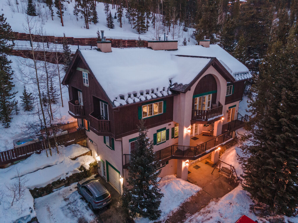 Exterior of mountain lodge hotel tucked into snowy mountainside surrounded by pine trees. Breckenridge Boutique Hotel, Breckenridge, Colorado.