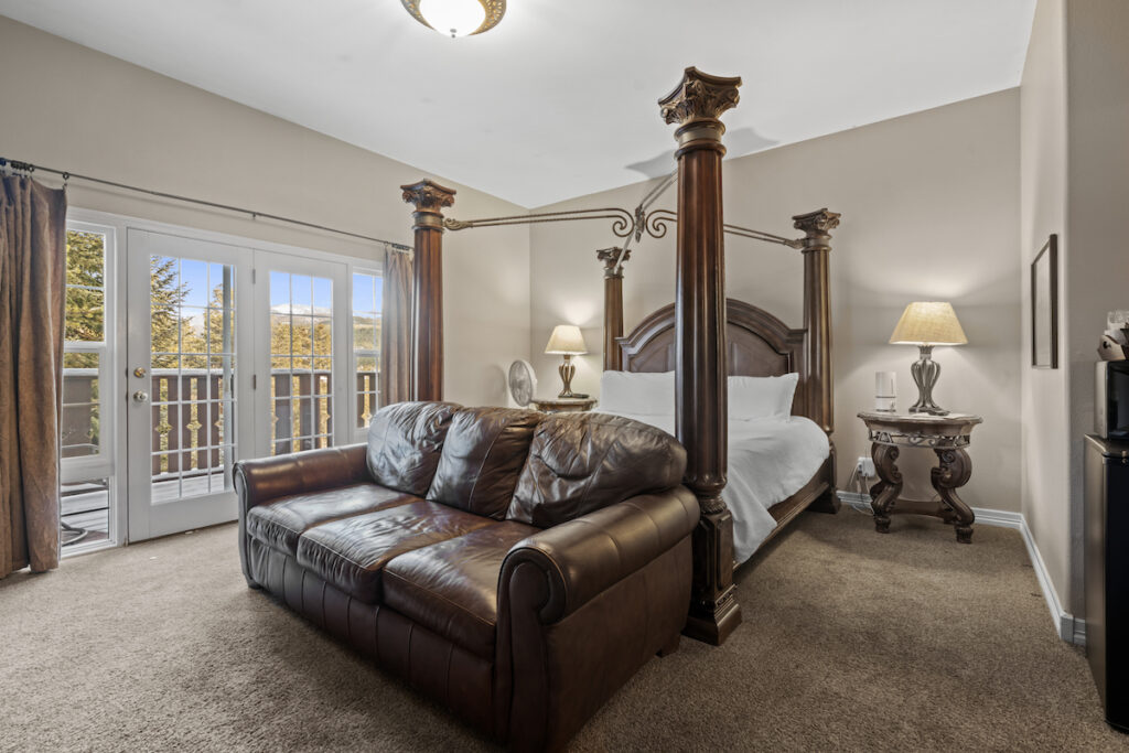 Luxury hotel guest room with large king size bed, leather couch, and mountain view patio. Breckenridge Boutique Hotel, Breckenridge, Colorado.