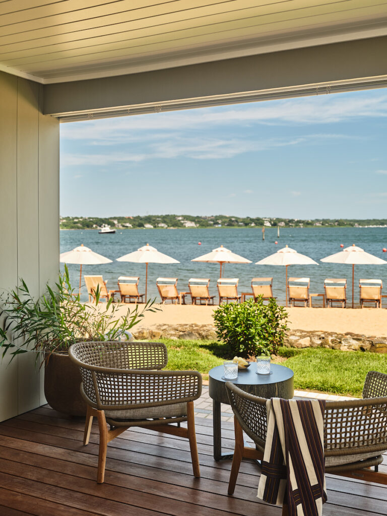 Guest balcony with upscale seating area overlooking lake beach lined with umbrellas and beach chairs. Montauk Yacht Club resort, Montauk, New York, The Hamptons.