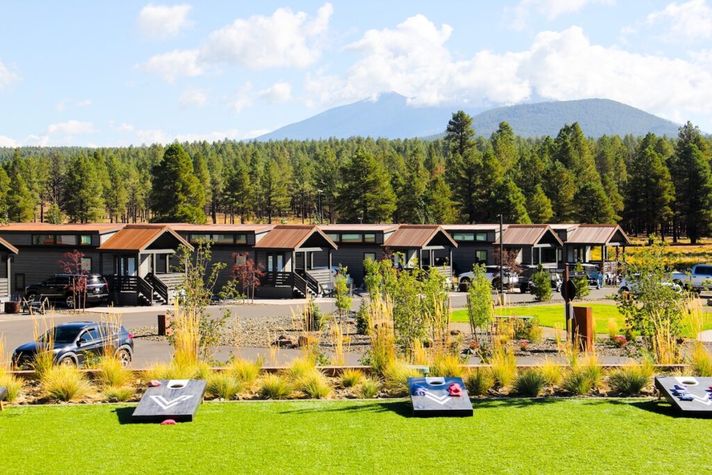 Row of cabins and games with forest and mountain background on sunny day. Village Camp Flagstaff, Bellemont, Arizona.