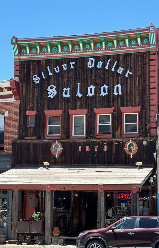 Historic wooden building with colorful trim and large sign reading "Silver Dollar Saloon" on sunny summer day. Silver Dollar Saloon, Leadville, Colorado.