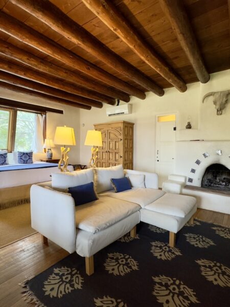 Luxury hotel guest suite with spacious living area, fireplace, and wood beamed ceiling. Luxury bed and breakfast hotel, Old Taos Guesthouse, Taos, New Mexico.